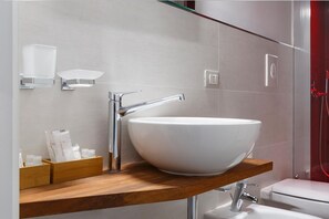 Un baño moderno con un lavamanos blanco de diseño, accesorios cromados y un mueble de tocador de madera.