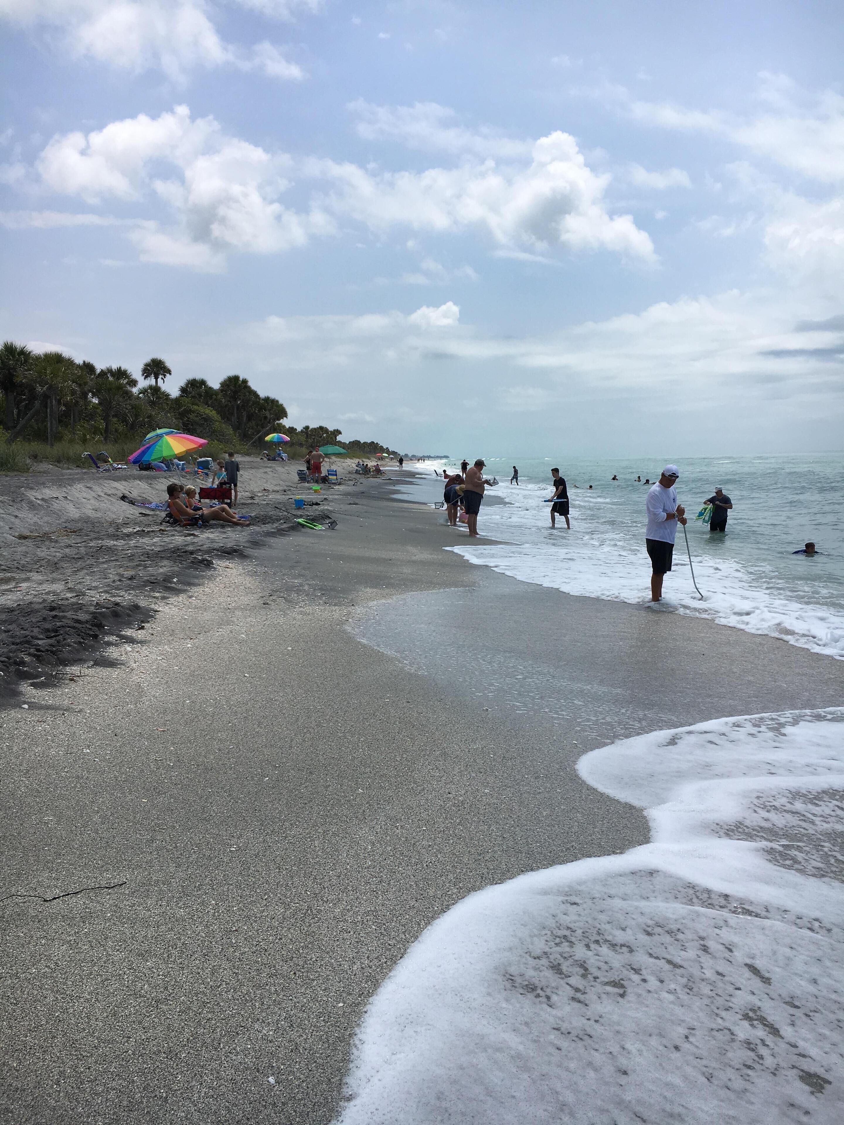 Une plage où l’on peut voir des gens se détendre et se baigner, ainsi que des parasols et des chaises de plage.