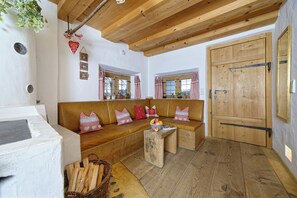 A cozy room with a wooden ceiling, a large wooden door, and a brown sofa with patterned cushions. - Cozy, cozy apartment near Chiemsee (Eggstätt)