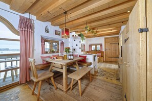 Uma mesa de jantar de madeira com bancos, vista para o exterior e decoração rústica.