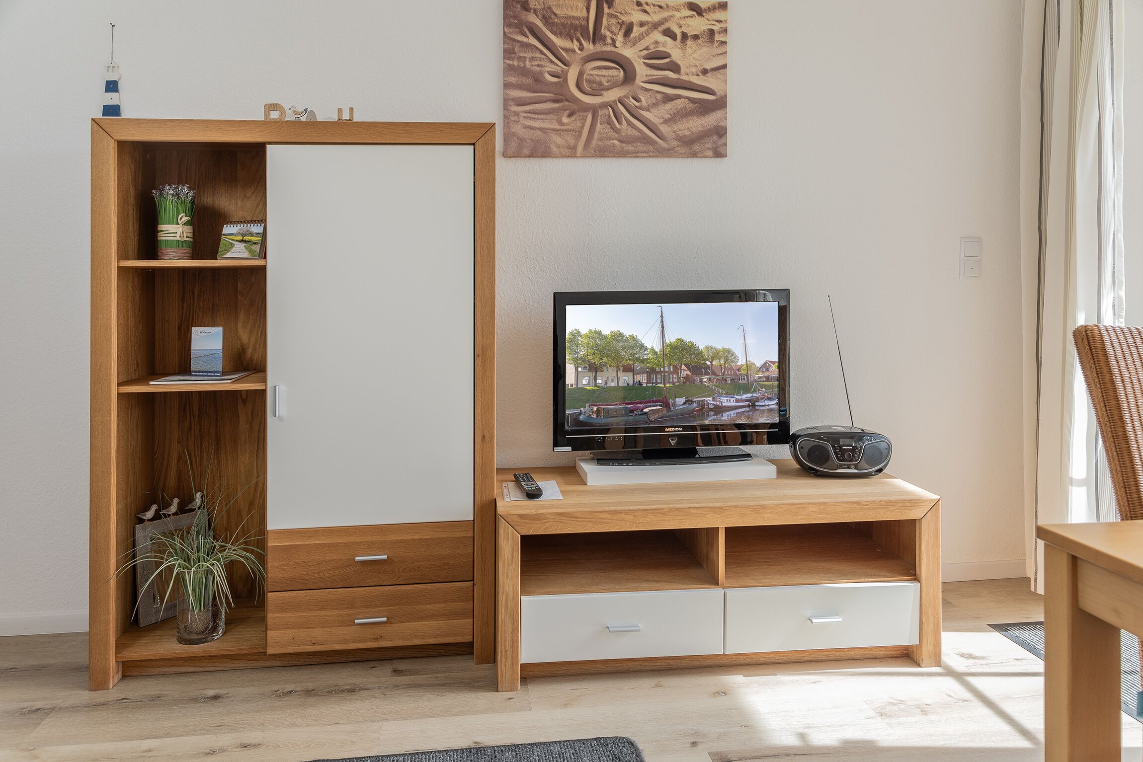 Una sala de estar moderna con una unidad de entretenimiento de madera, un televisor de pantalla plana y una radio.