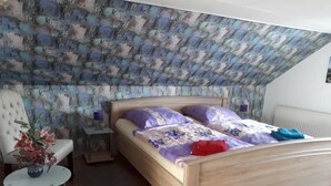 Une chambre à coucher avec un lit en bois, une chaise, une petite table avec une lampe et un vase décoratif.