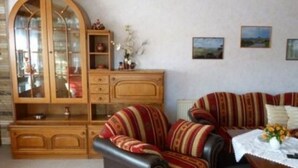 Un salon comprenant un ensemble de canapés, un meuble en bois et une table sur laquelle est posé un vase.