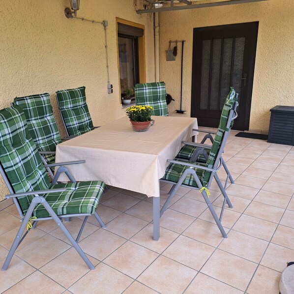 A patio with a table and chairs, a potted plant, and a door. - Holiday house Luise in Sebntz (Sebnitz)