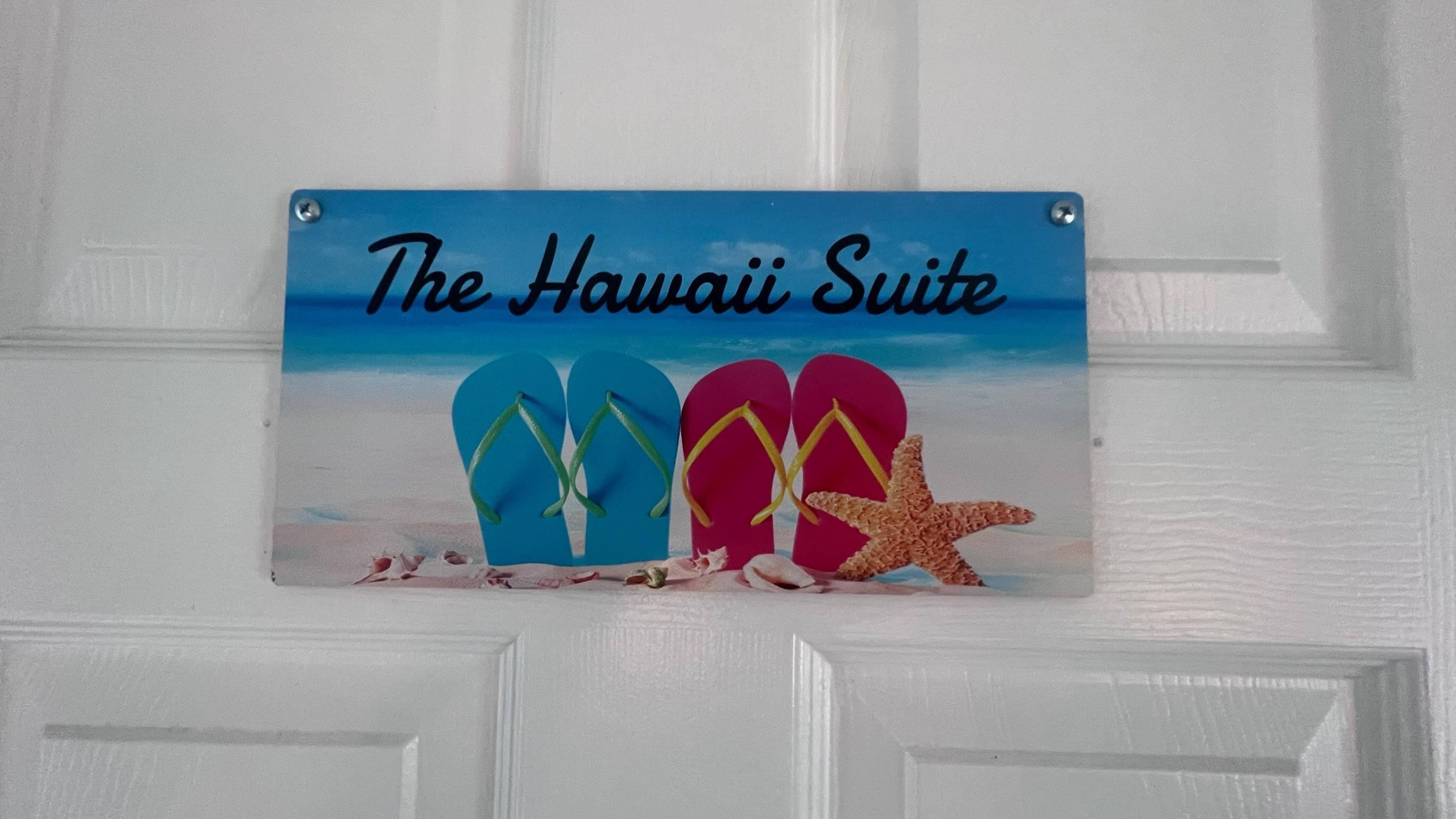A door sign with 'The Hawaii Suite' text and a beach scene with flip-flops and a starfish.