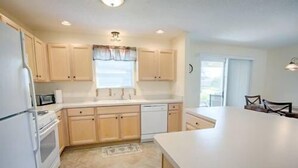 Una cocina moderna con armarios de madera clara, una isla central y un lavavajillas empotrado.