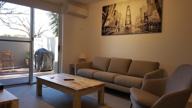 Een woonkamer met een bank, een salontafel en een schilderij aan de muur.