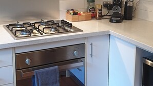 Een moderne keuken met witte kastjes, een gasfornuis, een oven en een magnetron.