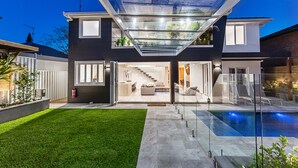 Une maison moderne dotée d’un patio entièrement vitré, d’une piscine et d’une pelouse bien entretenue.