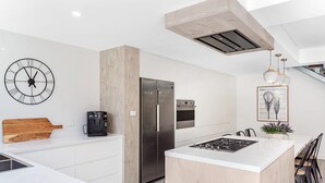 Une cuisine moderne dotée d’un îlot central, d’appareils électroménagers en acier inoxydable et d’une horloge murale.