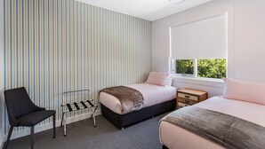 Une chambre moderne avec un papier peint à rayures, un lit, une chaise et une fenêtre donnant sur un paysage agréable.