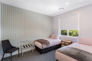 Een moderne slaapkamer met gestreept behang, een bed, een stoel en een raam met uitzicht.