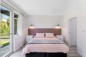 A bedroom with a bed, bedside tables, and a window. - La Luna Shoal Bay Luxury Holiday Home with Pool (Shoal Bay)
