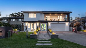 Une maison moderne à deux étages, dotée d’un garage, d’une pelouse bien entretenue et d’un chemin menant à l’entrée.