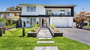 Une maison moderne à deux étages, dotée d’un garage, d’une cour avant avec un chemin et d’un petit jardin.