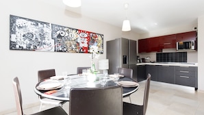 A modern dining area with a round table, chairs, and a large abstract painting on the wall.