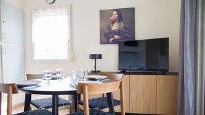 Un coin repas avec une table ronde, quatre chaises, un téléviseur et un tableau accroché au mur.