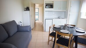 Un espace de vie compact comprenant un coin cuisine, un coin repas avec une table et des chaises, et un canapé.