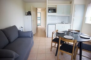 Een compacte leefruimte met een kitchenette, een eethoek met een tafel en stoelen, en een bank.