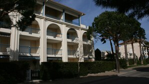 Un hôtel à plusieurs étages, doté d’une façade blanche, de balcons bleus et surplombant un ciel dégagé.