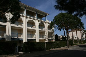 Een meerlaags hotel met een witte gevel, blauwe balkons en een heldere lucht.