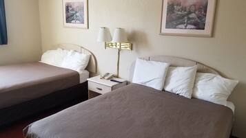 Una habitación de hotel con dos camas, una mesita de noche con una lámpara y dos cuadros enmarcados en la pared.