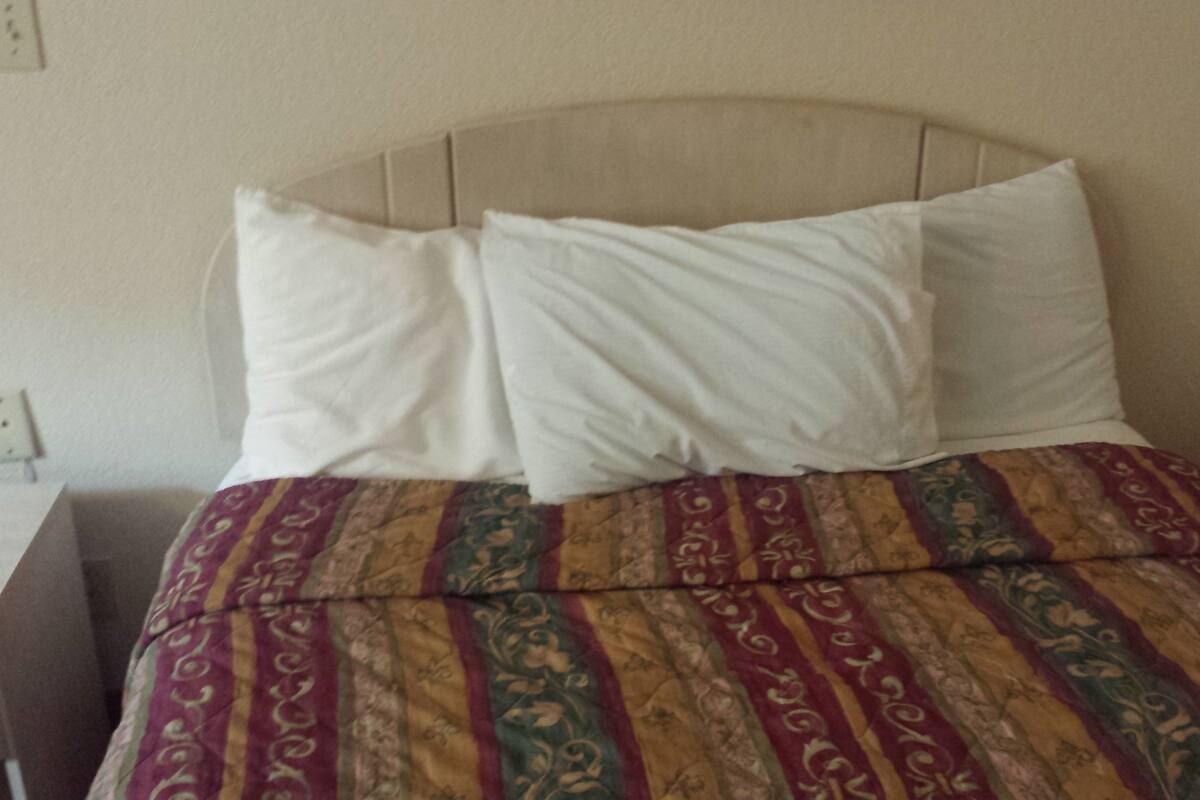 A bed with a patterned bedspread and two white pillows.