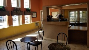 A restaurant interior with orange walls, tiled floors, and a counter area. - Americas Stay Inn (Leavenworth)
