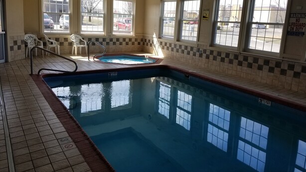 An indoor swimming pool with tiled walls, windows, and a lifeguard sign. - Americas Stay Inn (Leavenworth)