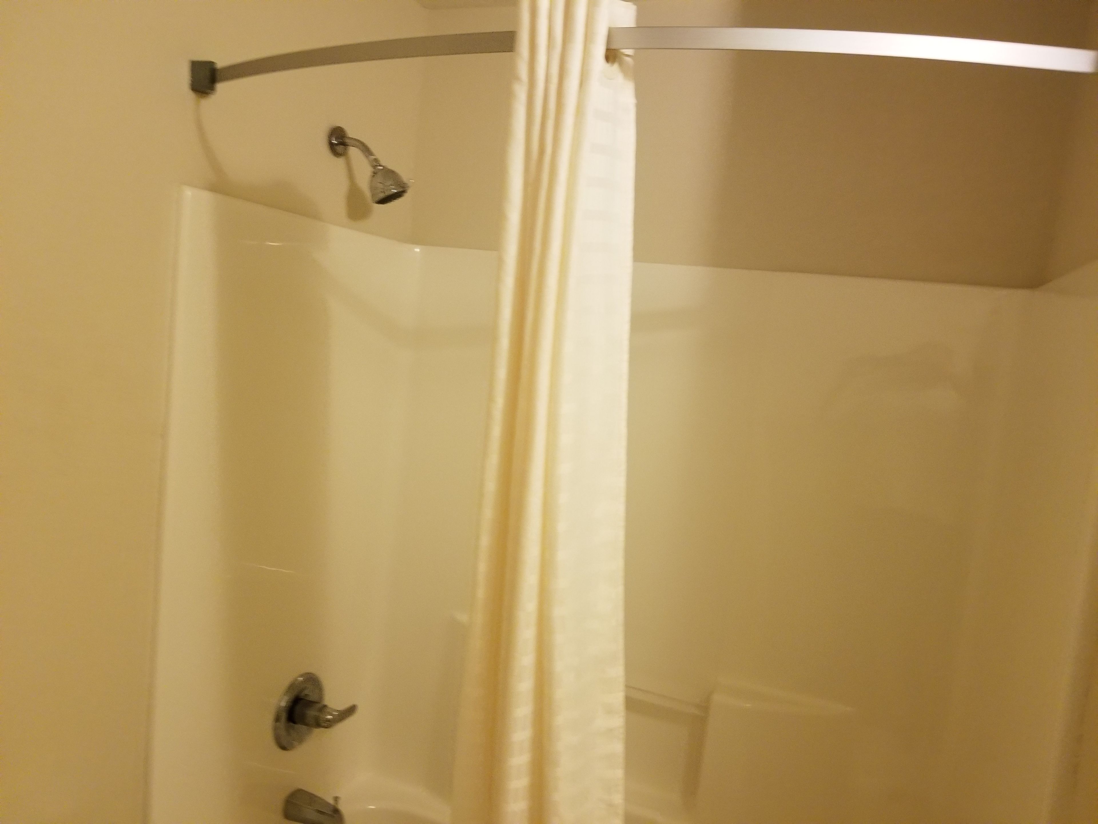 A shower with a glass door, a showerhead, and a curtain rod.