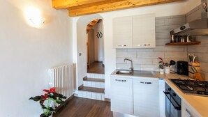 Een moderne keuken met witte kastjes, een houten plafond en een zichtbare trap die naar een andere kamer leidt.