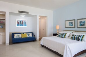 Une chambre d’hôtel comprenant un lit, un canapé, une table de chevet, une lampe et une porte donnant sur un placard.
