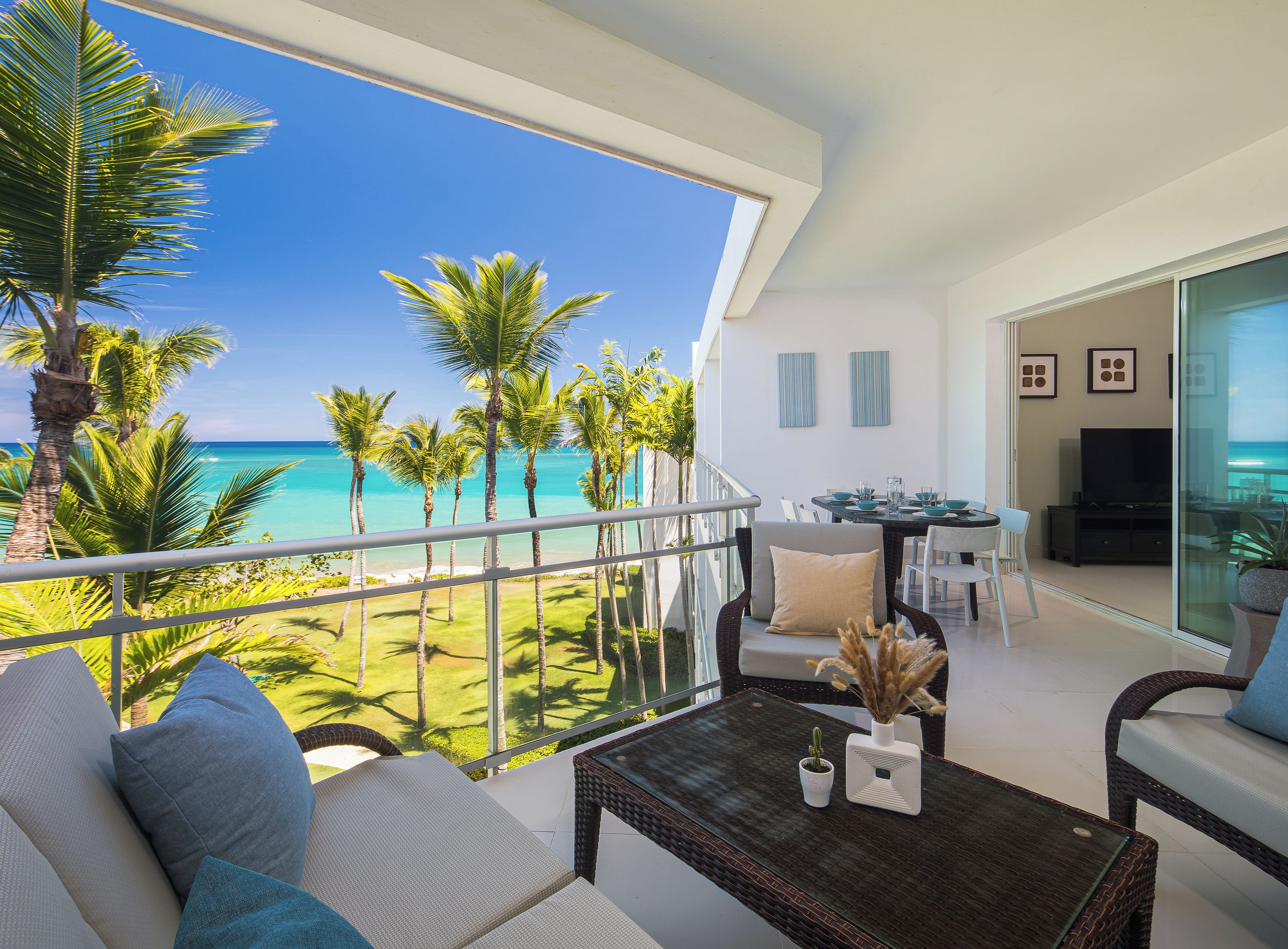A balcony with a view of the ocean, furnished with a sofa, chairs, and a table.