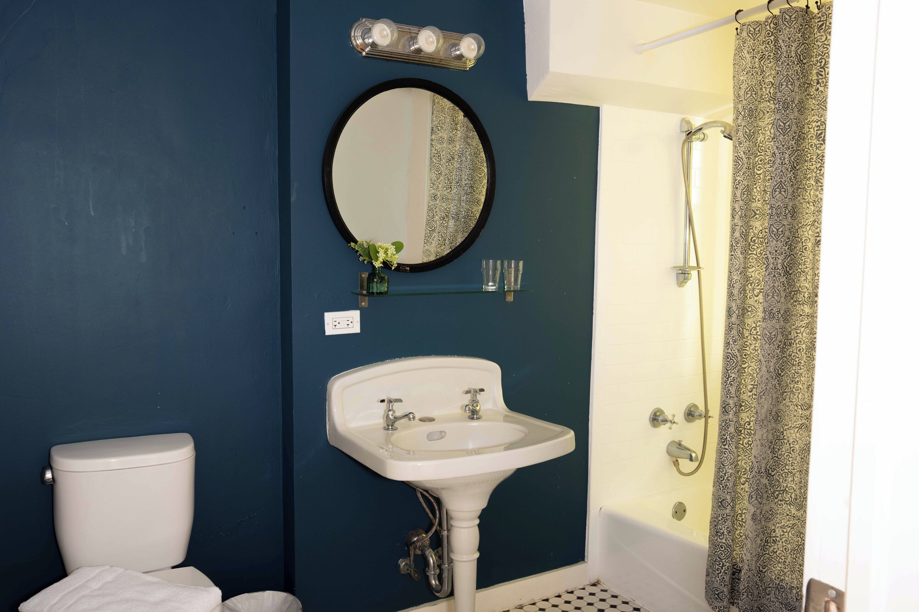 A bathroom with a white sink, a round mirror, and a shower curtain.