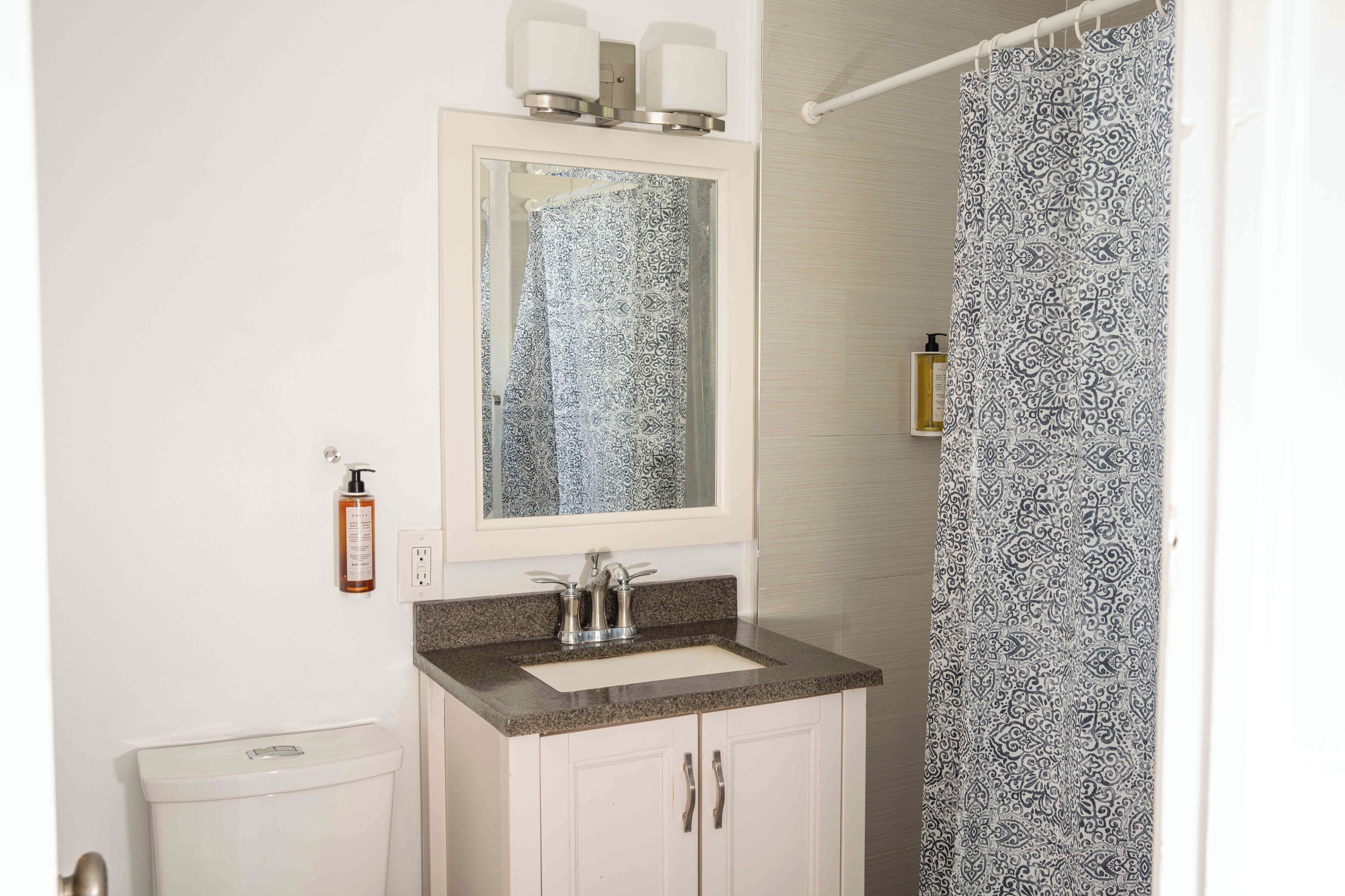 Une salle de bain avec un lavabo, un miroir et un rideau de douche.
