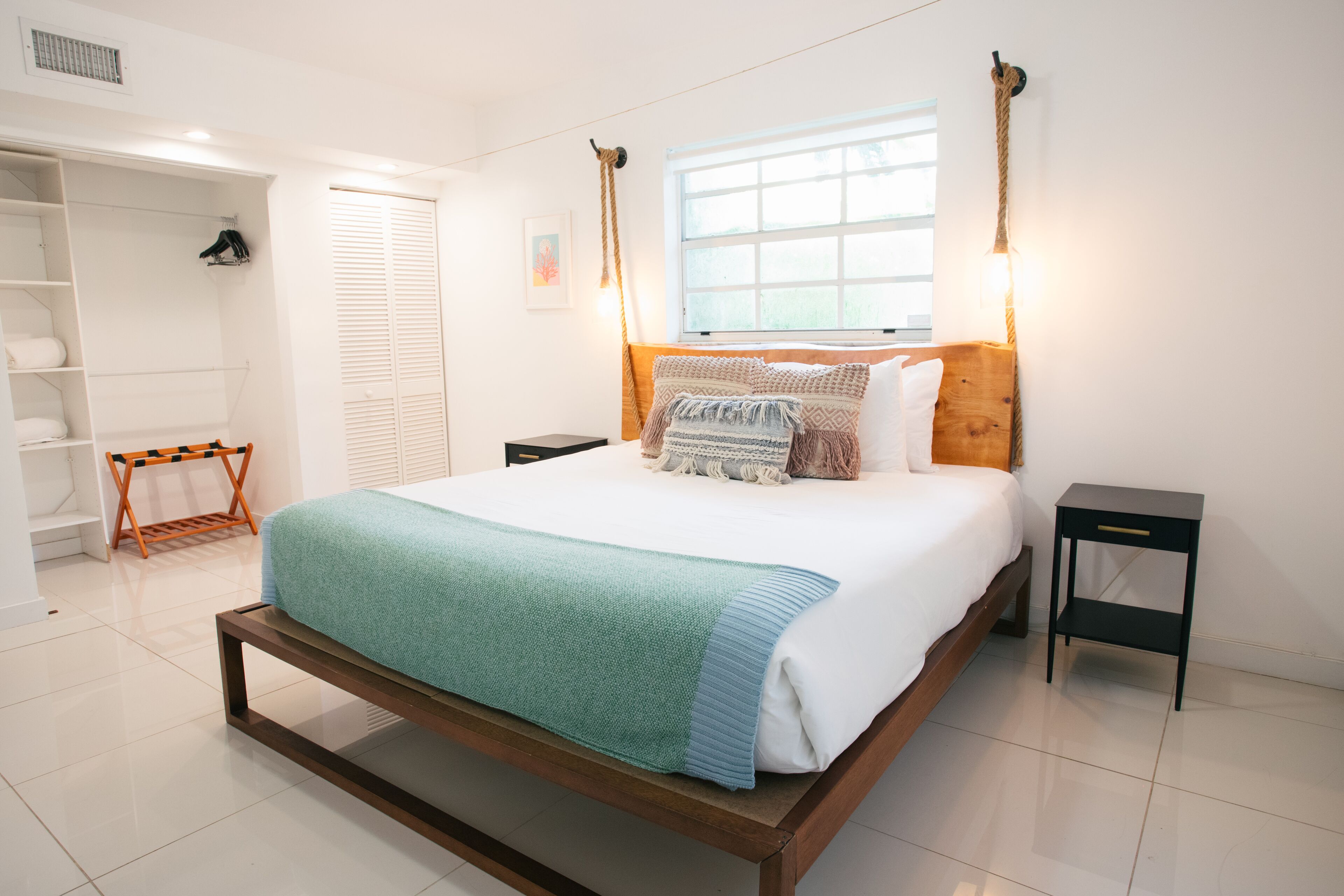 Een slaapkamer met een bed, nachtkastjes, een kledingkast en een raam met natuurlijk licht.
