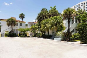 A hotel courtyard with palm trees, a reception area, and a building with a tiled roof.