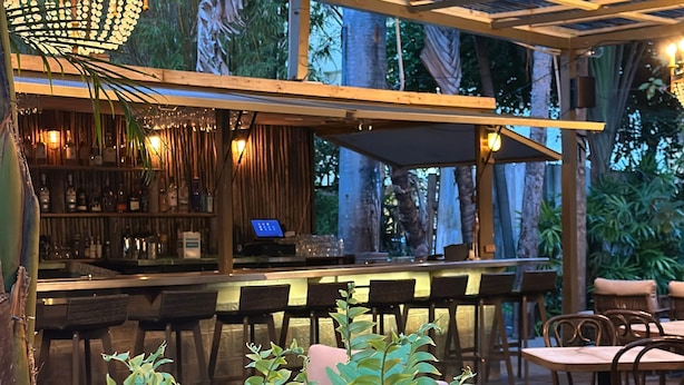 An outdoor bar area with a wooden pergola, bar stools, and a chandelier. - Miami River Inn By Renzzi (Miami)