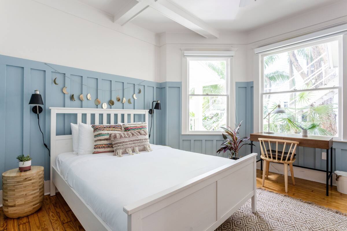 Een slaapkamer met een bed, nachtkastjes, een bureau en een stoel.