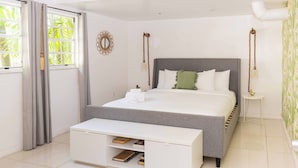 A modern bedroom with a grey bed, white bedside tables, and a white console table with books. - Miami River Inn By Renzzi (Miami)