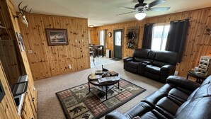 A wooden-paneled room with a leather sofa, a coffee table, and a ceiling fan. - 40 Creek Lodge North at Waubay Lake (Waubay)