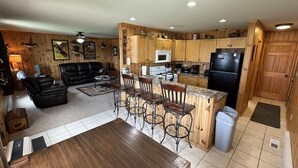 A spacious kitchen with wooden cabinets, a dining area with a wooden table, and a bar area with stools. - 40 Creek Lodge North at Waubay Lake (Waubay)