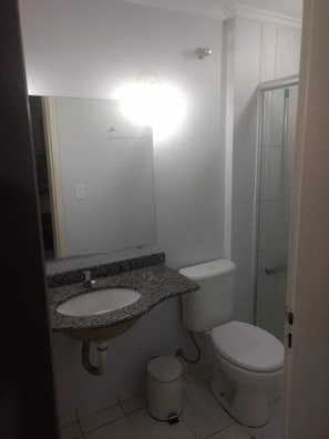 A bathroom with a granite countertop sink, a white toilet, and a small trash can. - Thermas Place Diamante (Caldas Novas)