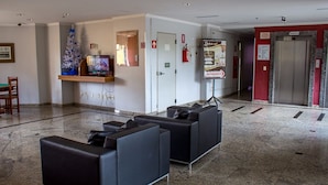 Eine Lobby mit einer Rezeption, einem Fernseher, einem Feuerlöscher und einem Aufzug.