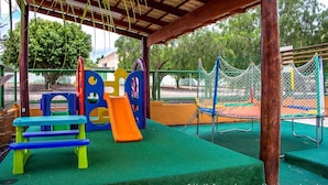 Ein Spielplatz mit Rutsche, Klettergeräten und Trampolin.