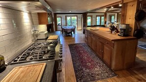 A modern kitchen with a gas stove, wooden cabinets, and a dining area with a table and chairs.