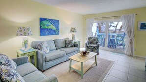 A living room with a sofa, armchairs, a coffee table, and a painting of a fish.