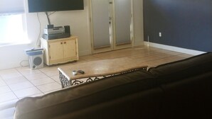 Ett vardagsrum med en takfläkt, en tv som är monterad på väggen, ett skåp och en skjutdörr.