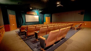 A movie theater with rows of seats, a large screen, and a stage area.