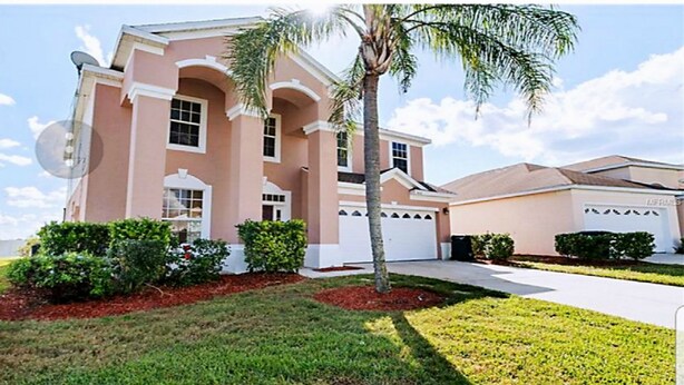 A two-story house with a garage, a satellite dish, and a well-maintained lawn.